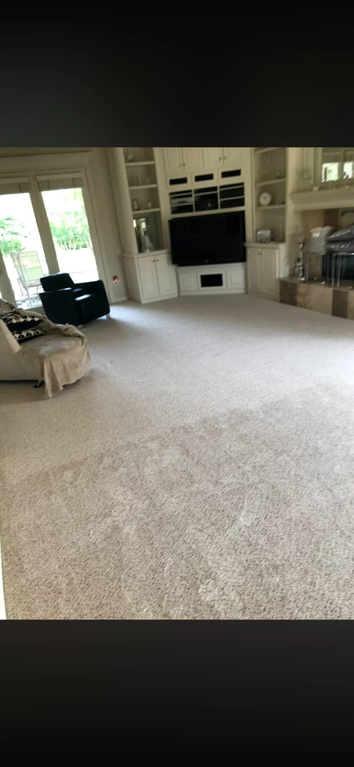 Beige carpet in large living room with built-in white cabinetry and media wall