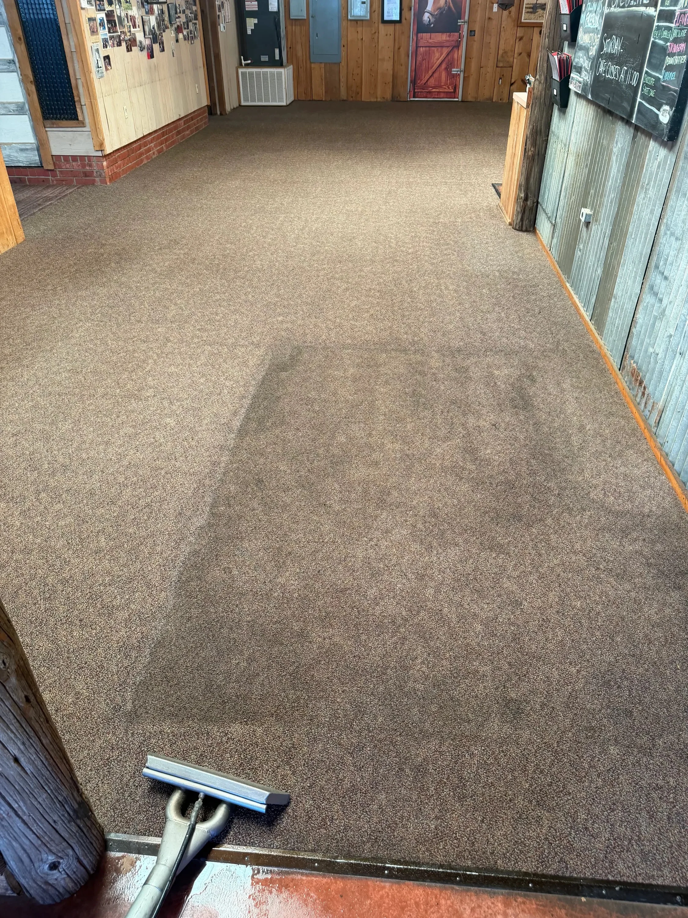 Commercial carpet cleaning in progress with extraction equipment on tan carpet flooring