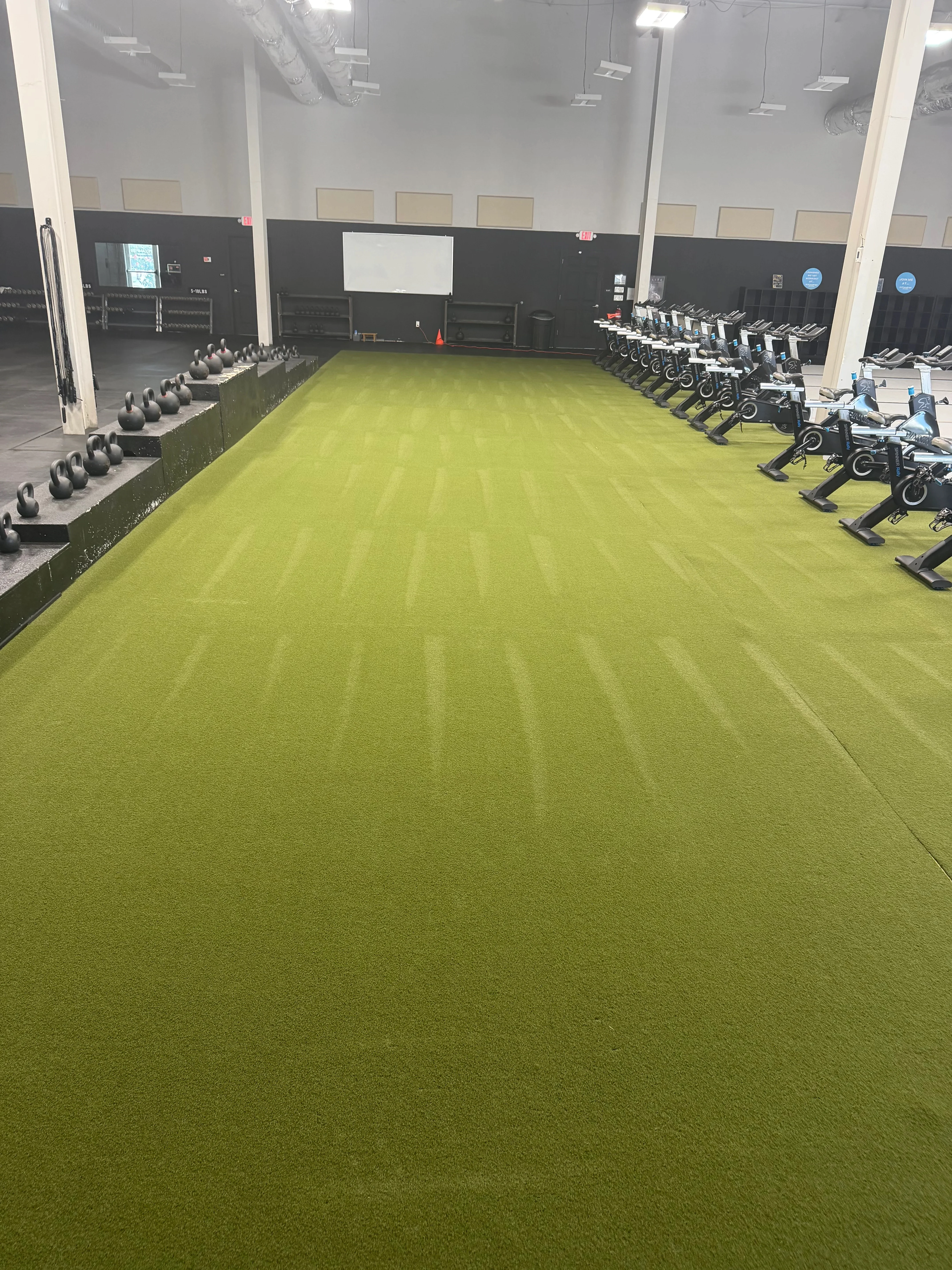 Bright lime-green commercial carpet with visible stripe pattern in fitness facility with equipment