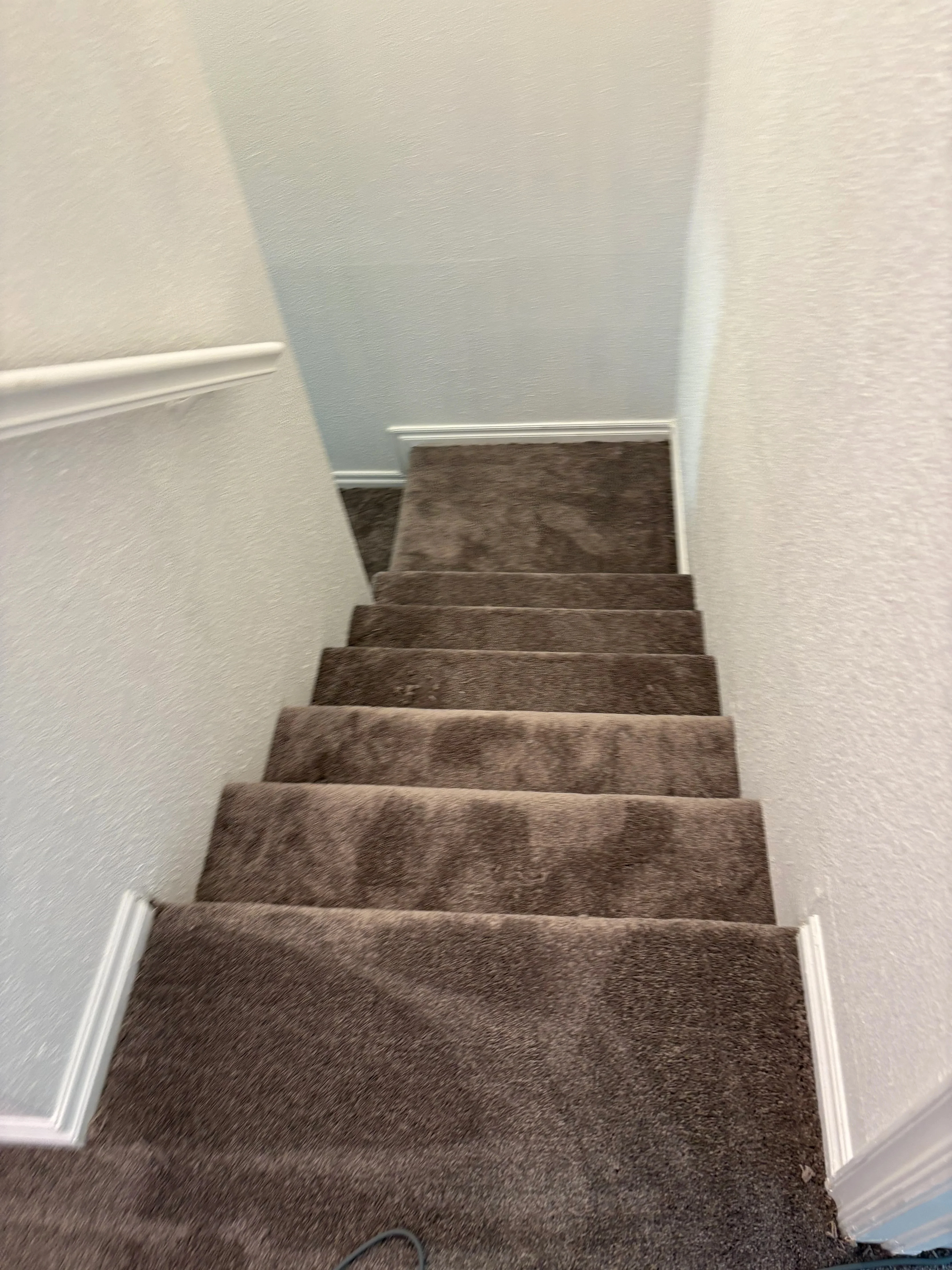 Charcoal gray textured carpet installed on residential staircase with white trim and baseboards